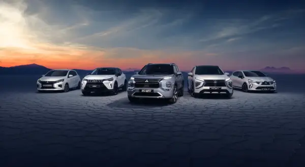 Pięć modeli Mitsubishi ustawionych na pustynnym tle o zachodzie słońca.