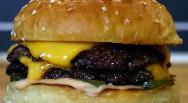 En saftig smashed burger med dubbla köttpuckar, smält ost, pickles och dressing. Perfekt för en hungrig dag!