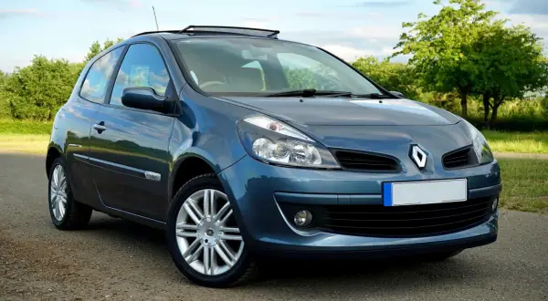 Un Renault Clio azul aparcado en un camino rural. El coche tiene un techo solar y llantas plateadas.
