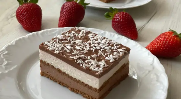 Czekoladowo-śmietankowy deser z mascarpone i wiórkami kokosowymi, ozdobiony truskawkami.