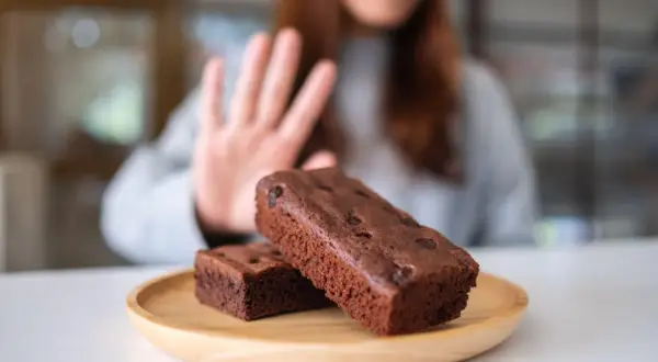 Kobieta odrzuca brownie, wybierając dietę bez cukru.