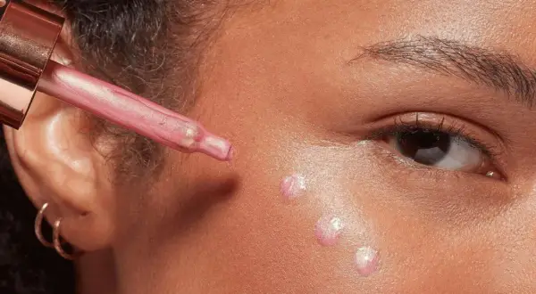 Applicazione di illuminante liquido sul viso con contagocce per un look radioso.