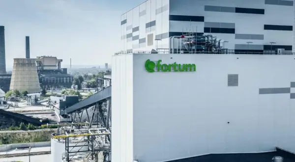 Nowoczesna elektrociepłownia Fortum, gdzie powstaje zielony prąd, z charakterystycznym logo. W tle widać kominy i chłodnie kominowe.