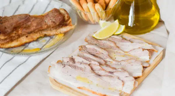 Chicharrón de Cádiz, crujiente y jugoso, servido con limones y palitos de pan.