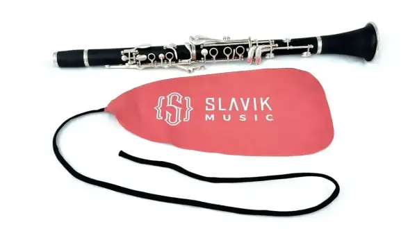 Elegancki klarnet leży obok różowego pokrowca z logo Slavik Music. Obój i klarnet to instrumenty dęte drewniane.