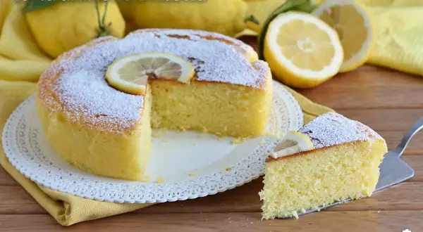 Torta soffice alla ricotta e limone, spolverata di zucchero a velo e decorata con una fetta di limone.