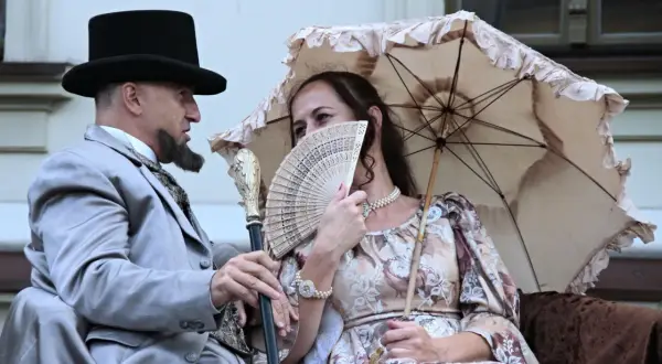 Para z epoki, mężczyzna w cylindrze i eleganckim garniturze, kobieta z wachlarzem i parasolką. Ich stylizacja to lalka opracowanie.