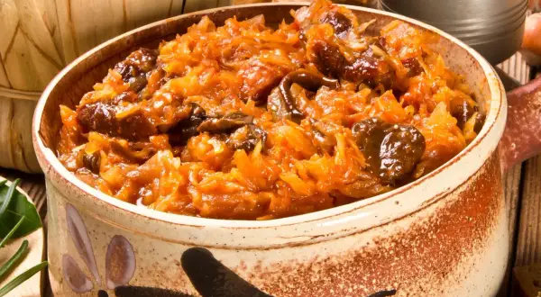 Pyszny bigos bez mięsa w glinianym naczyniu, pełen kapusty i grzybów.