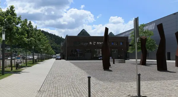 Die Halle 32 mit ihren markanten Glaspyramiden, umgeben von Bäumen und Skulpturen, an einem sonnigen Tag.