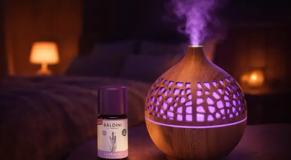 Ein Diffusor verströmt lila Dampf, daneben eine Flasche Baldini Lavendelöl. Perfekt für Lavendel Entspannung im Schlafzimmer.