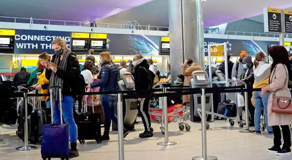 Kolejka do odprawy na lotnisku. Ludzie z bagażami czekają na swoją kolej, by nadać paczkę do UK.