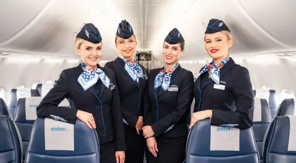 Uśmiechnięte stewardessy Enter Air w granatowych mundurkach i chustach z logo linii. Czy Enter Air jest bezpieczny? Tak, z taką załogą podróż będzie komfortowa.