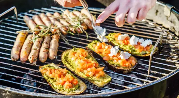 Kiełbaski i bakłażany z pesto i pomidorami pieką się na grillu. Idealne blachy na grilla na letnie popołudnie.