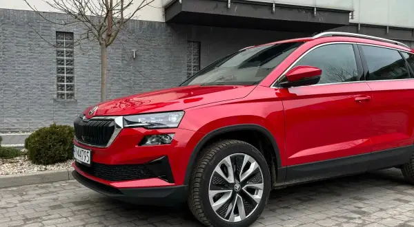 Czerwona Skoda Karoq na tle nowoczesnego budynku. Wiele osób szuka skoda karoq opinie, by podjąć decyzję o zakupie.
