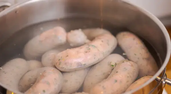 Kiełbasa gotuje się w garnku. Dowiedz się, ile parzyć kiełbasę, by była idealna.