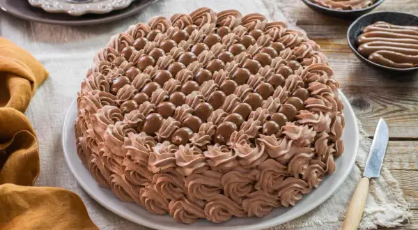 Torta decorata con abbondante crema chantilly al cioccolato e praline. Un dolce invitante pronto per essere gustato.