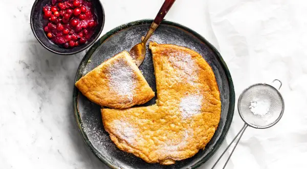 Puszysty omlet, posypany cukrem pudrem, z żurawiną obok. Idealny przepis na pyszne śniadanie.