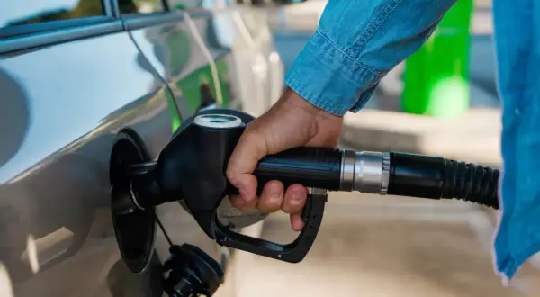 Dłoń trzymająca pistolet paliwowy przy samochodzie. Czas na zimowe paliwo od kiedy? Przygotuj auto na mrozy.