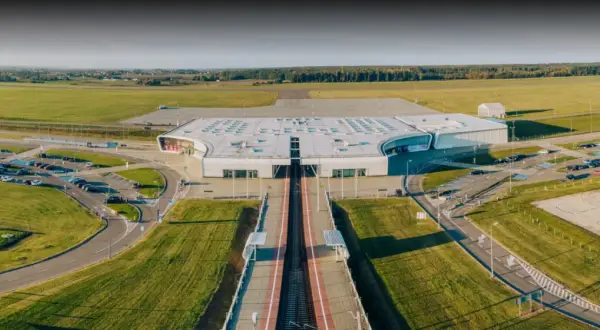 Nowoczesny terminal lotniska w Lublinie, otoczony polami i parkingami.