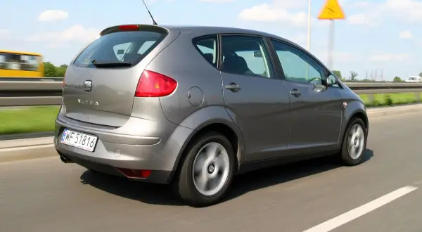 Szary Seat Altea 1.9 TDI w ruchu drogowym, z widocznym znakiem ostrzegawczym.