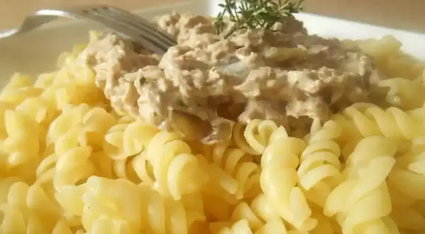 Pâtes fusilli généreusement garnies d'une sauce crémeuse aux pâtes au thon, décorées d'une branche de thym.