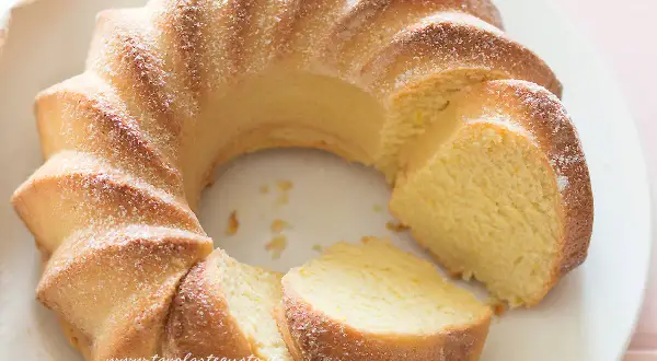 Una soffice torta di ricotta, spolverata di zucchero a velo, con una fetta tagliata che ne rivela la morbidezza.