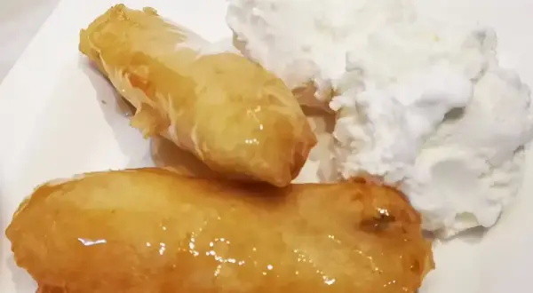 Två gyllene friterade bananer med honung serveras med en generös klick vaniljglass. En ljuvlig dessert!
