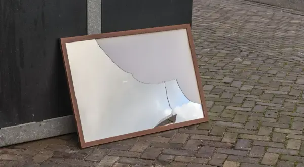 Zepsute lustro w drewnianej ramie leży na bruku. Czy lustro można wyrzucić do szkła?