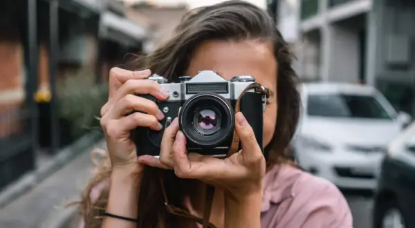Dziewczyna z aparatem w rękach, idealna do kursu fotografii dla początkujących.