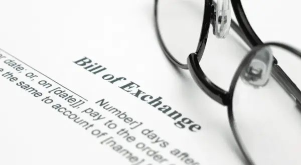 Okulary leżą na dokumencie "Bill of Exchange". To jest weksel, czyli papier wartościowy, który zobowiązuje do zapłaty określonej sumy pieniędzy.