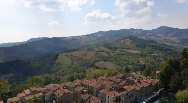 Panoramica di un borgo con tetti in cotto e colline verdi. Un assaggio di cosa vedere sul Monte Amiata, tra natura e storia.