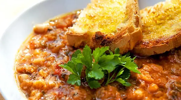En närbild av en skål med mustig ribollita, toppad med rostat bröd och färsk persilja. Ett perfekt ribollita recept för en kall dag.
