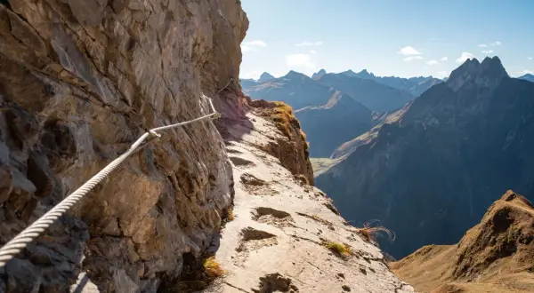 Klettersteig am Laufbacher Eck mit Seilsicherung und Blick auf schroffe Bergketten.