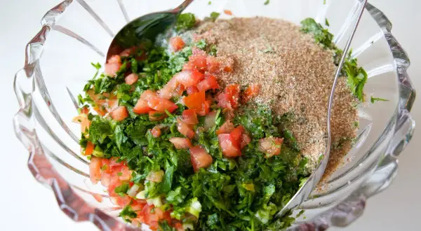 En skål med färska ingredienser för Zeinas tabbouleh: hackad persilja, tomat och bulgur.