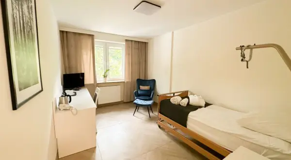 Pokój hotelowy z łóżkiem, biurkiem, fotelem i obrazem z lasem.