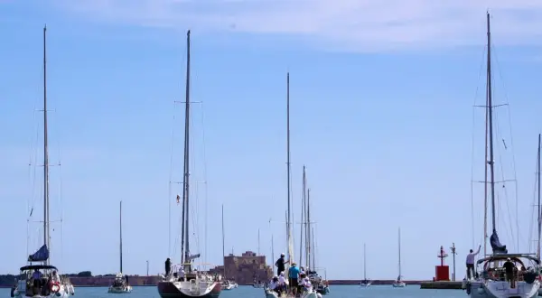 Veleggiate serene nella marina d'Angelo, con barche che solcano le acque azzurre sotto un cielo limpido.