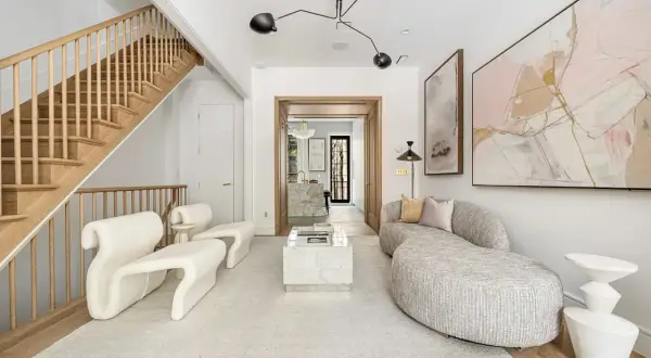 A living room showcasing minimalist interior design with a sculptural white sofa, a marble coffee table, and abstract art.