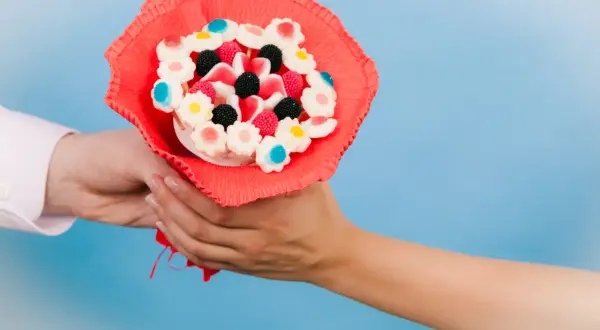 En person överlämnar en färgglad godisbukett, ett charmigt diy-projekt med blomformade geléhallon och bär.