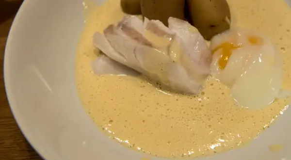 En portion torskrygg med pocherat ägg och potatis i en krämig sås. Perfekt för en middag med vin till torskrygg.