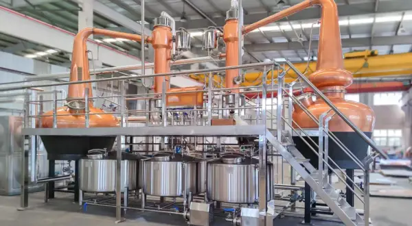 Nowoczesna instalacja do rektyfikacji z miedzianymi alembikami i stalowymi zbiornikami, gotowa do produkcji wysokiej jakości alkoholi.