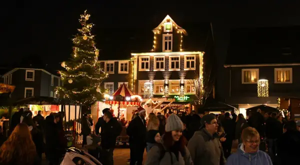 Menschen genießen den stimmungsvollen Radevormwald Weihnachtsmarkt mit beleuchtetem Baum und festlich geschmückten Häusern.