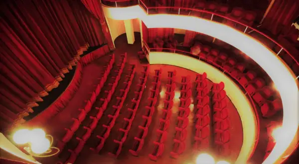 Interno del teatro cometa off, con file di poltrone rosse vuote e tende di velluto.