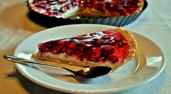 Pyszna tarta z mascarpone i owocami w galaretce, z łyżeczką gotową do degustacji.