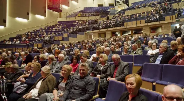 Widownia filharmonii pełna elegancko ubranych osób. Zastanawiasz się, jak się ubrać do filharmonii? Tutaj widzisz inspiracje: klasyczne stroje, garnitury, sukienki.