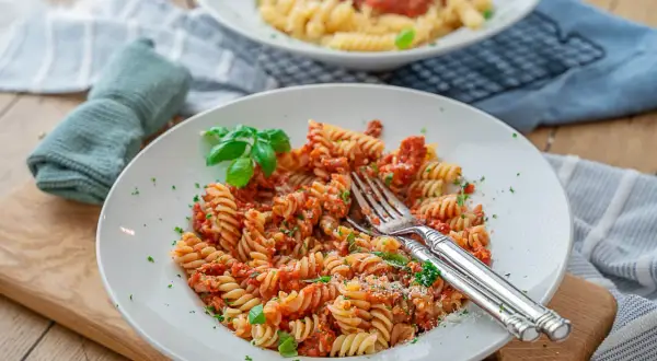 Eine köstliche Thunfisch Pasta mit Fusilli, Tomatensauce und frischem Basilikum, garniert mit Petersilie und Parmesan.