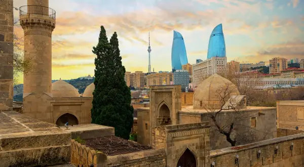 Zachód słońca nad Baku. Stare mury i minaret kontrastują z nowoczesnymi wieżowcami Flame Towers. Baku pogoda zachęca do zwiedzania.