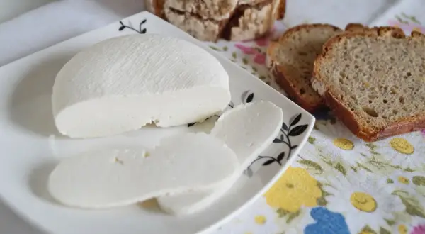 Świeży ser di bufala na talerzyku, obok kromki chleba.