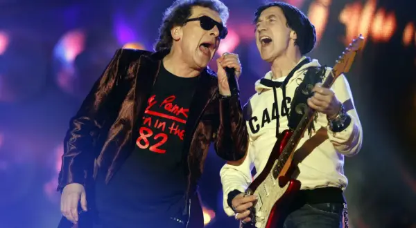 Na koncercie Lady Pank, wokalista w czarnej koszulce z napisem "Pank '82" i narzeczona w białej bluzie grają na gitarze.