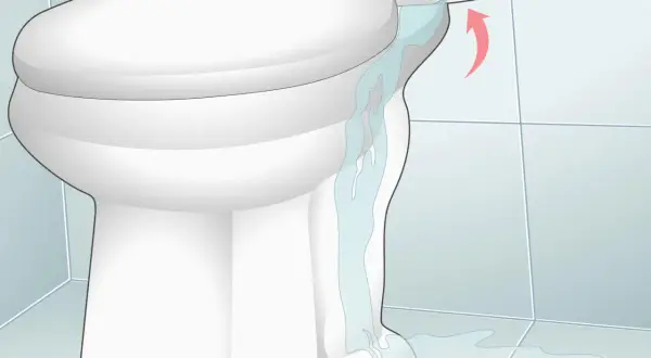 Water is leaking from a cracked toilet tank, causing low water in the toilet bowl and a puddle on the floor.
