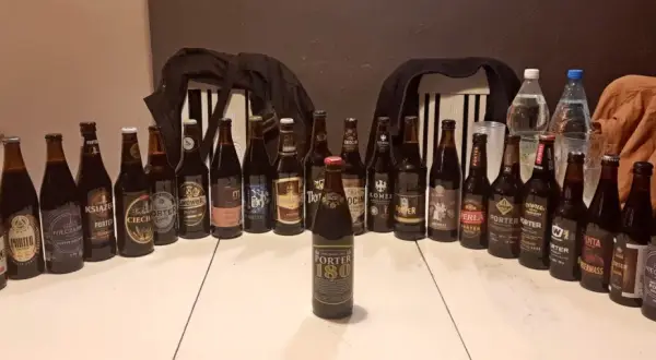 Stół zastawiony butelkami i puszkami piwa, idealny na dzień porteru bałtyckiego. Widać różne marki i etykiety.
